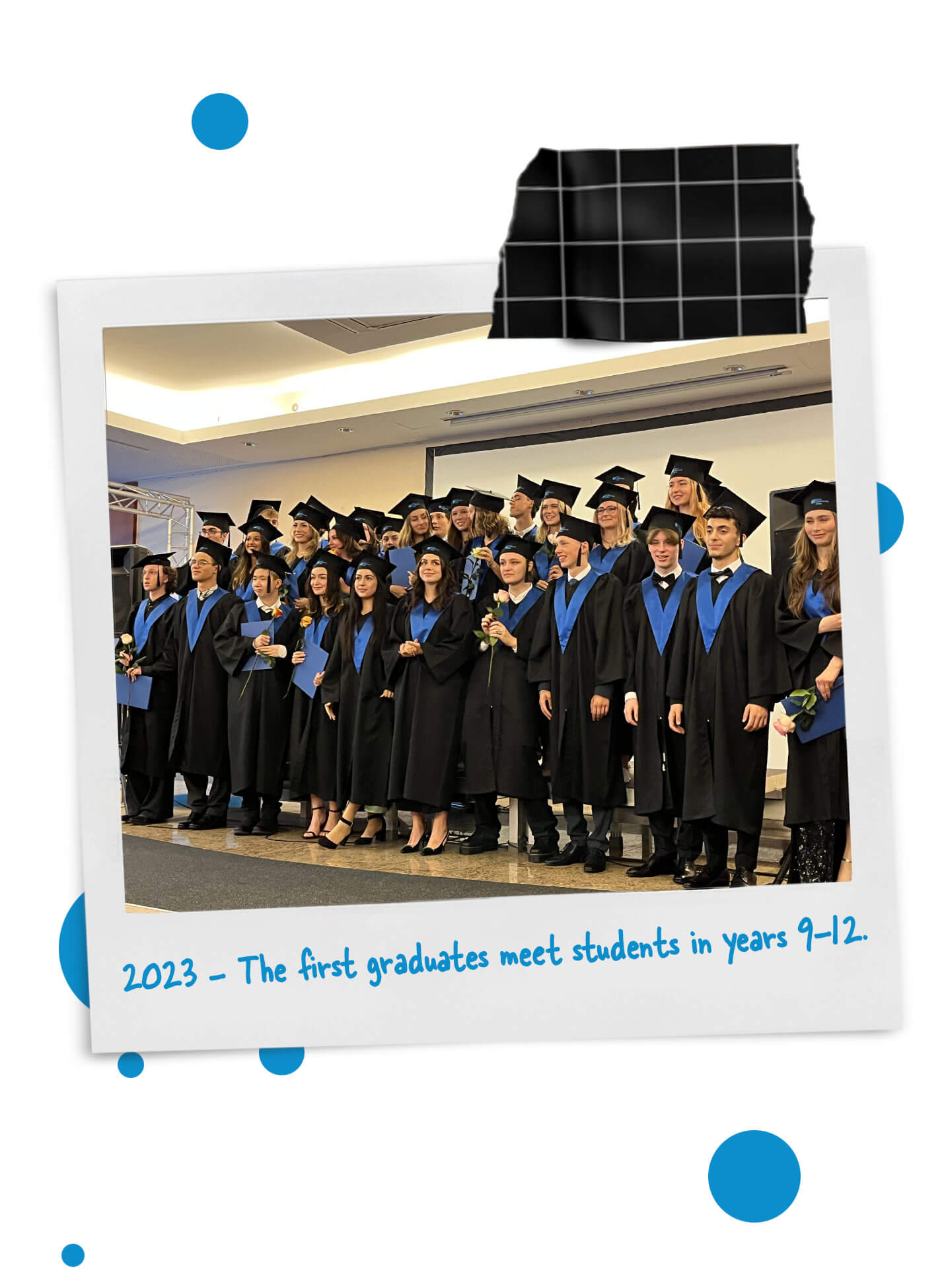 Cosmopolitanschool Berlin Eine Gruppe von Highschool-Absolventen in schwarzen Roben und mit Mörteln steht lächelnd auf der Bühne. Das Foto hat einen aufgeklebten Rahmen im Polaroid-Stil mit der Bildunterschrift: 2023 - Die ersten Absolventen treffen Schüler der Klassen 9-12. loading=