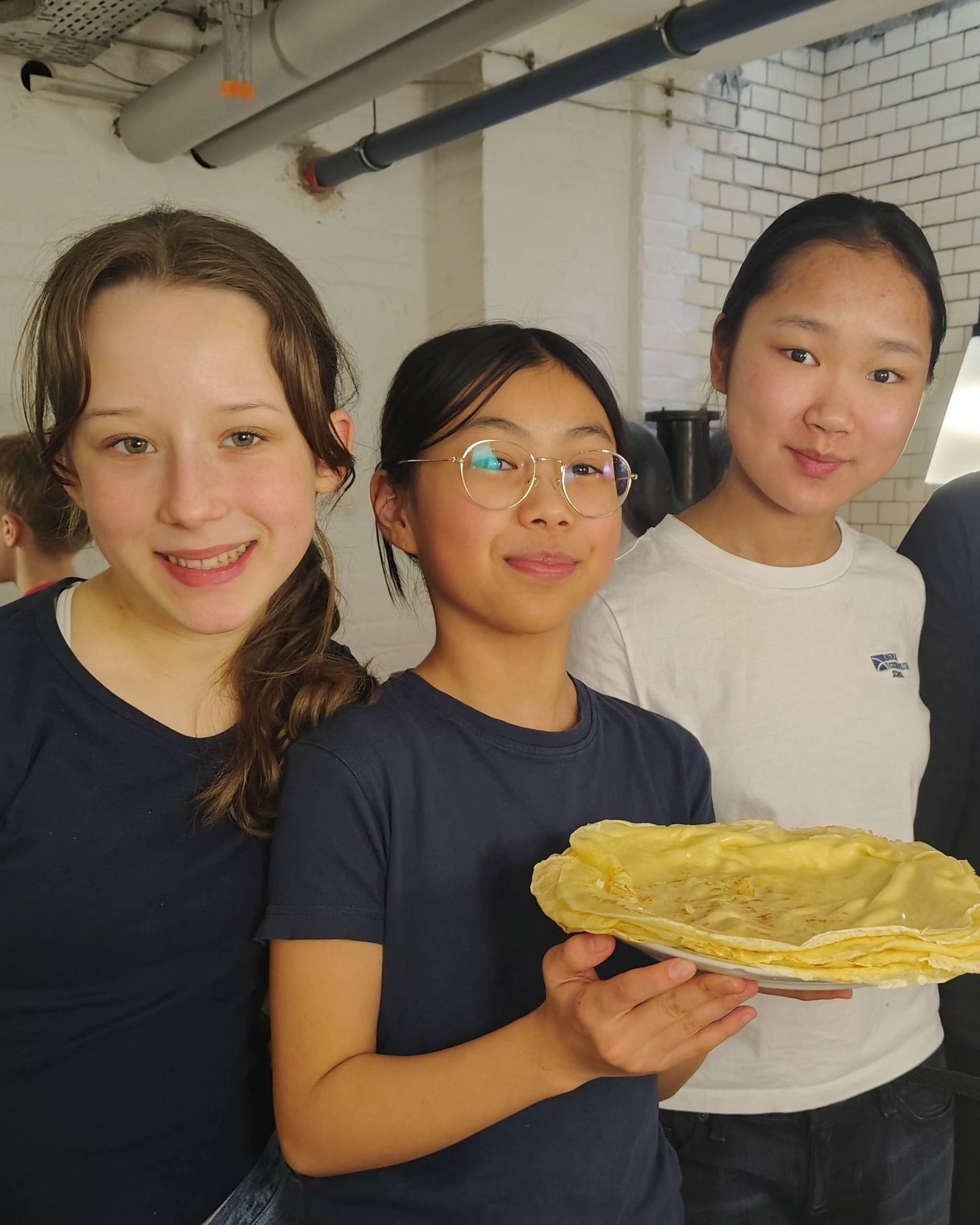 Drei Schülerinnen präsentieren einen selbst gebackenen Crepe loading=