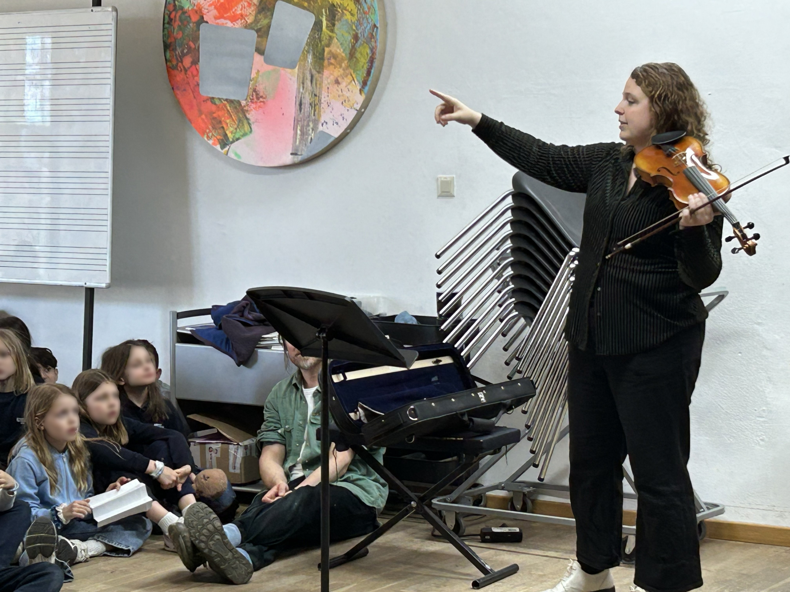 Cosmopolitanschool Berlin Eine Lehrerin spielt Geige vor einer Gruppe Schüler und Schülerinnen