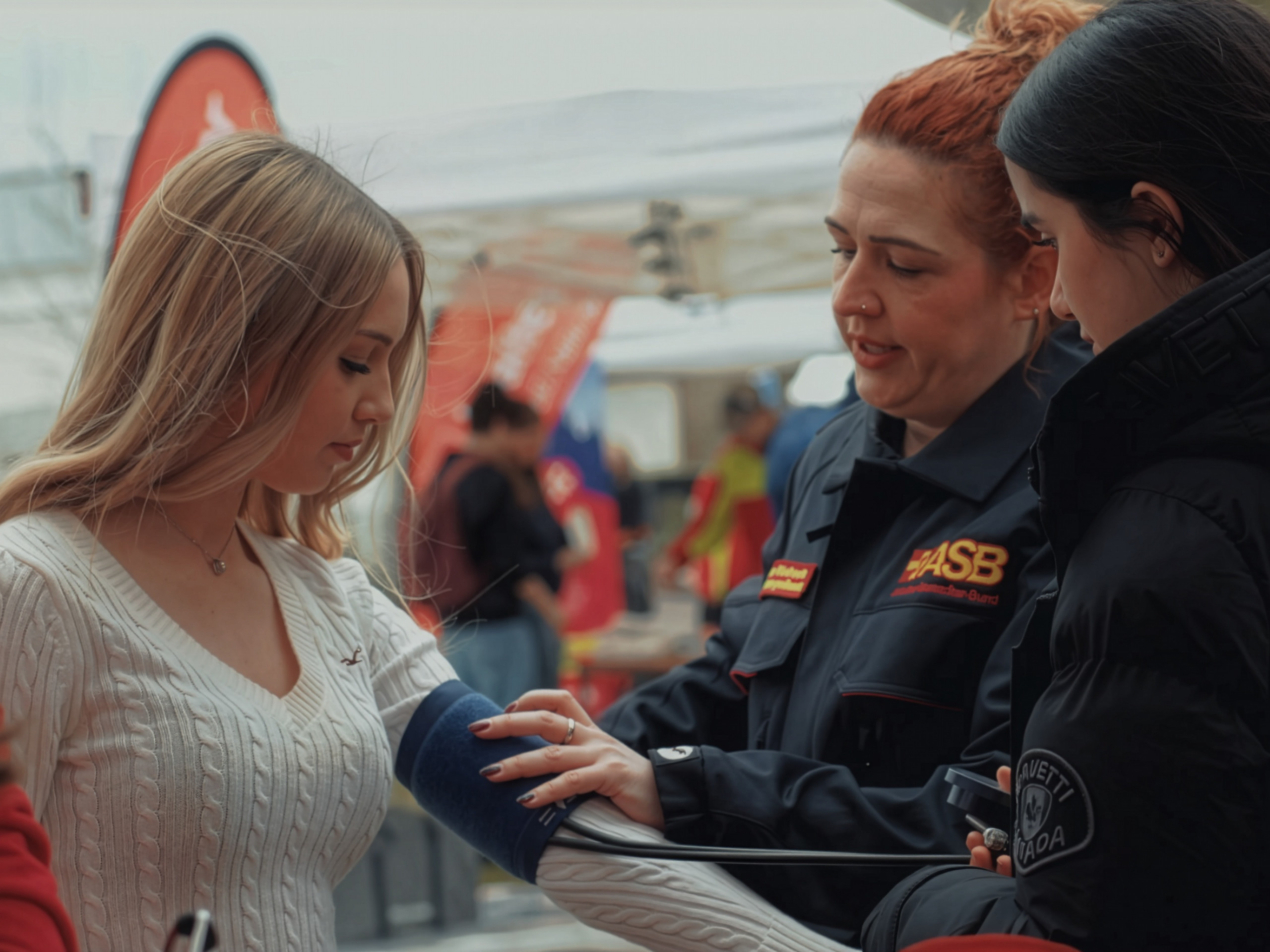 Einer Schülerin wird von zwei Personen der Blutdruck gemessen